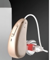 Supermini aparat słuchowy Muse 1200M RIC w etui ładującym z funkcją suszenia. Widoczne akcesoria: wkładki douszne, szczoteczka, kabel USB-C. Dyskretny model RIC dla osób z lekkim i umiarkowanym ubytkiem słuchu.